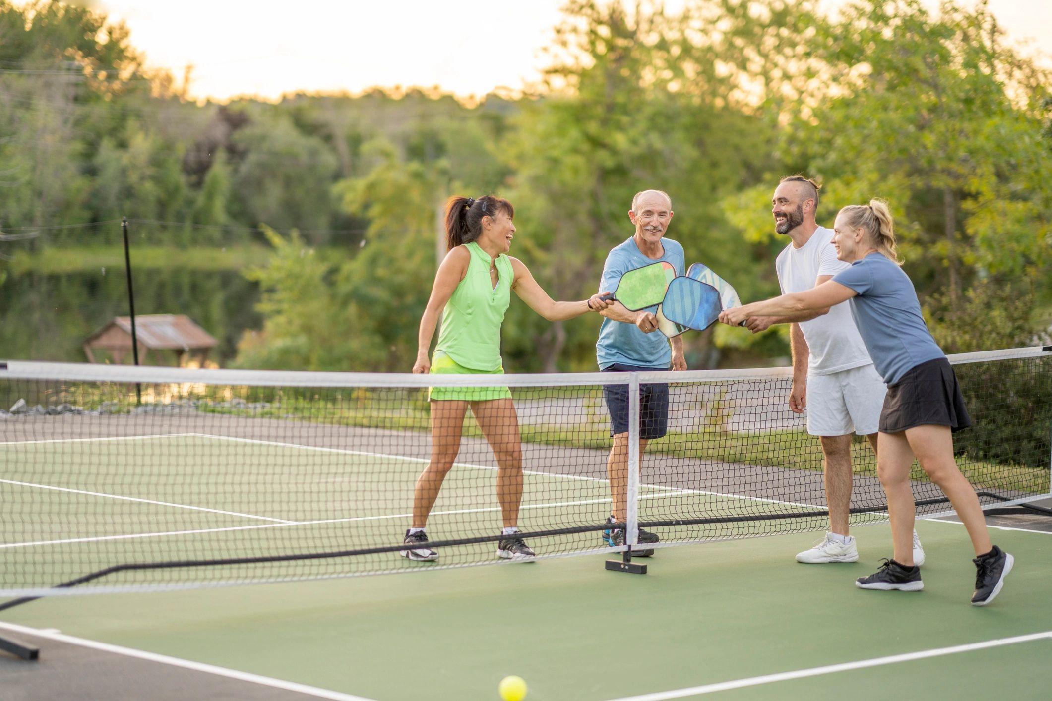 People playing pickleball outdoors on a sunny court